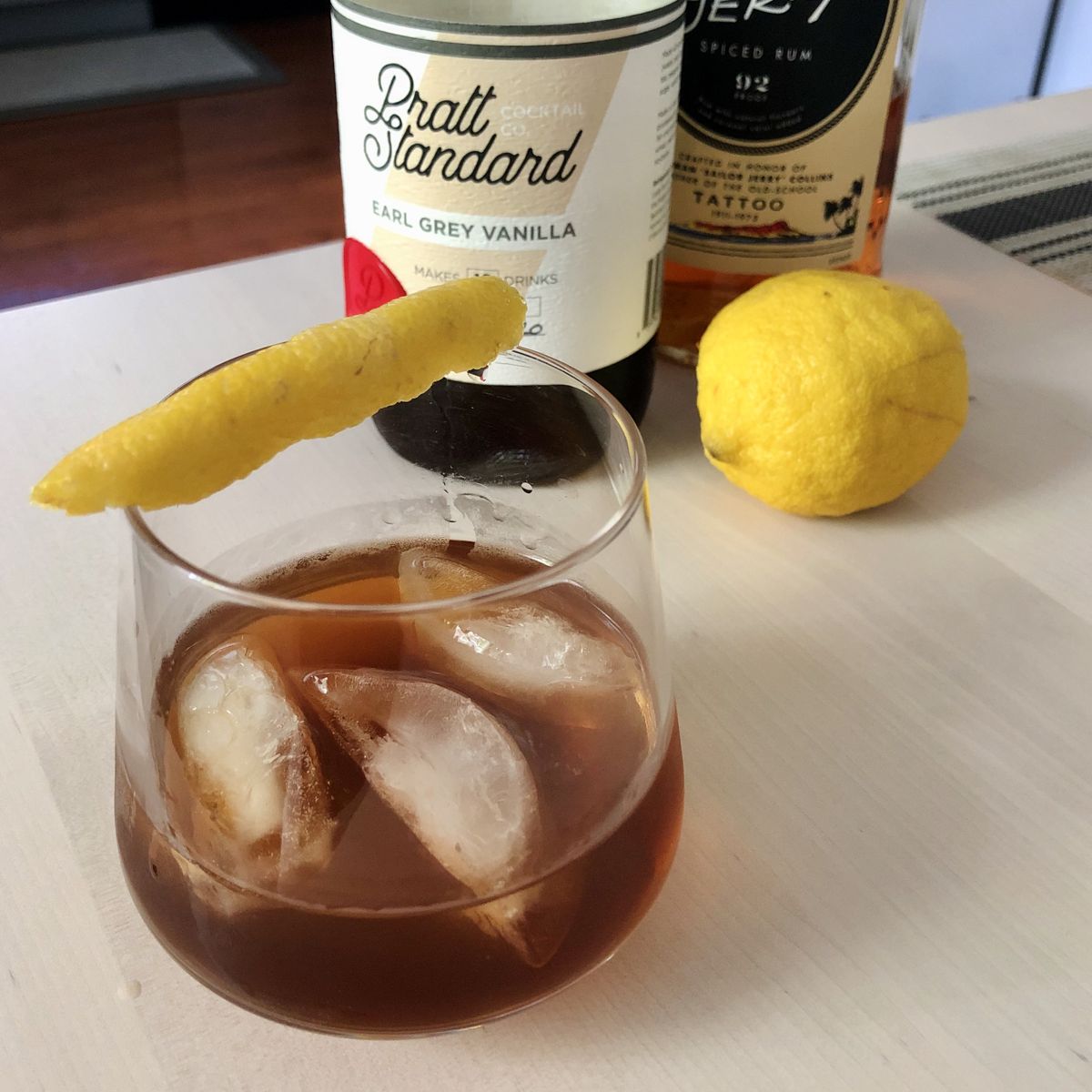 An Earl Grey Old Fashioned next to a bottle of Pratt Standard Earl Grey Vanilla syrup