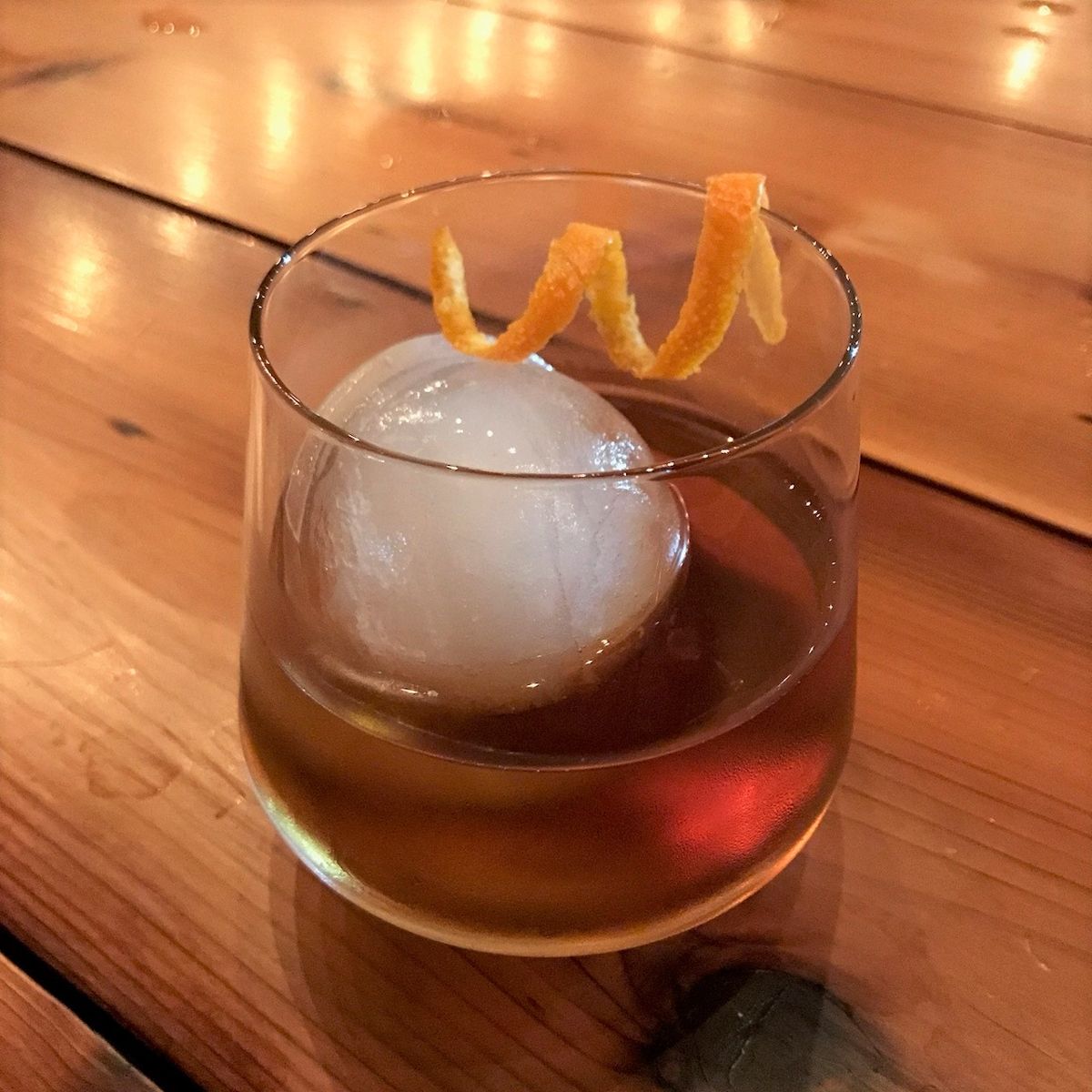 An Old Fashioned made with Pratt Standard Kola syrup, with an orange peel over a large ice cube